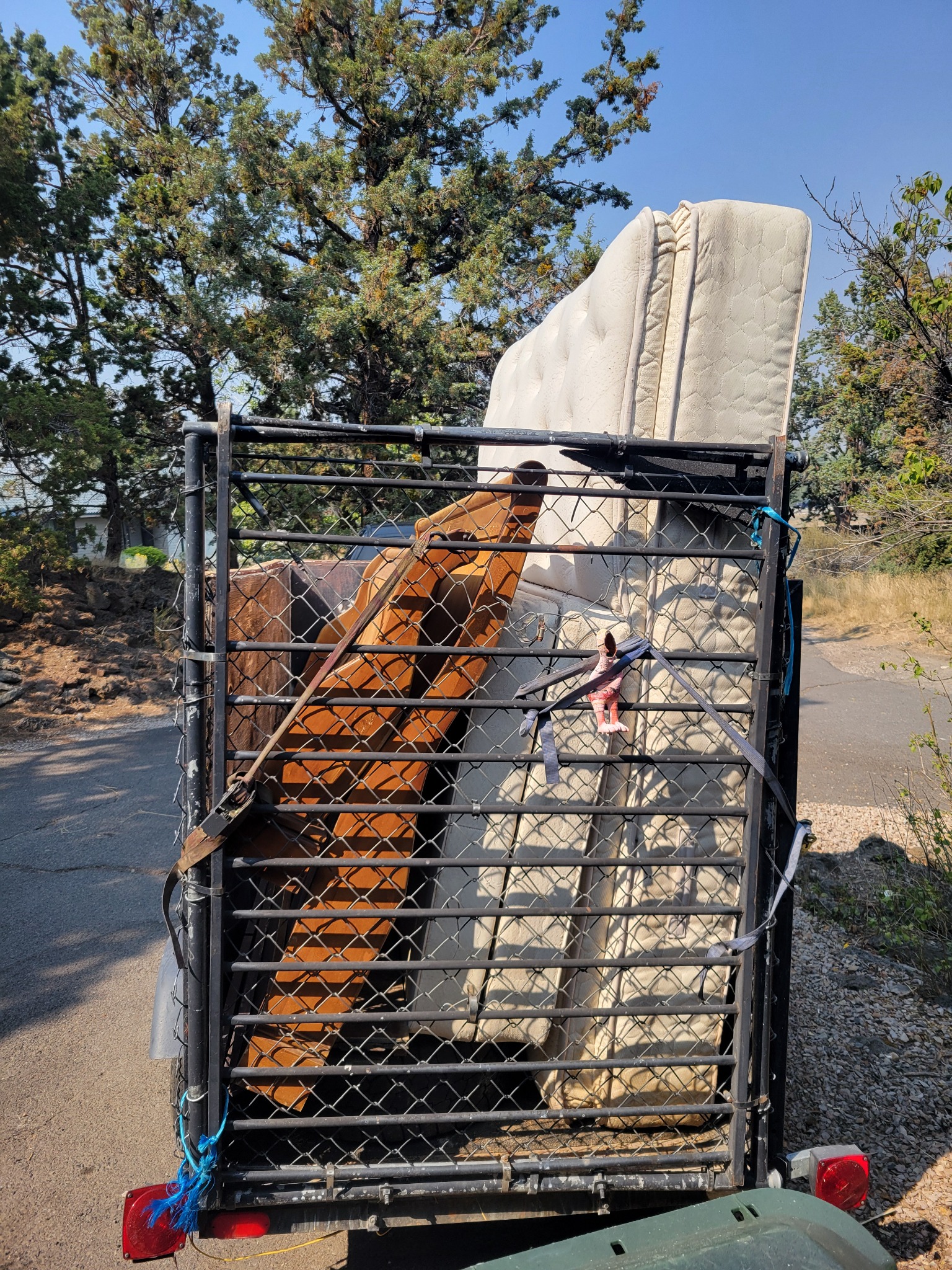 A Clear Haul trailer loaded with a mattress, box springs, and disassembled wooden furniture